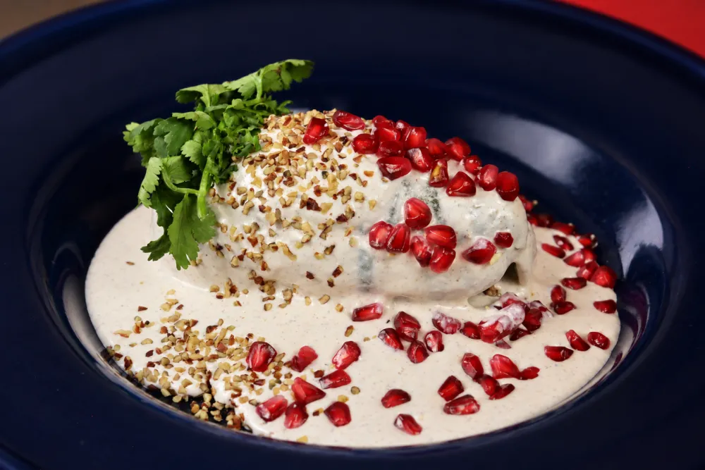 Chiles en Nogada de Delicias Marbe: chile poblano relleno bañado en nogada, con granada y perejil